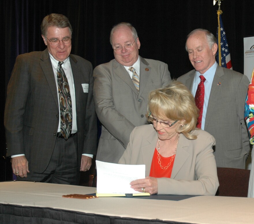 Gov. Jan Brewer signs legislation Friday with a package of tax cuts for business she said will stimulate the economy. Looking on are Sen. Steve Yarbrough, House Speaker Andy Tobin and Senate President Steve Pierce.