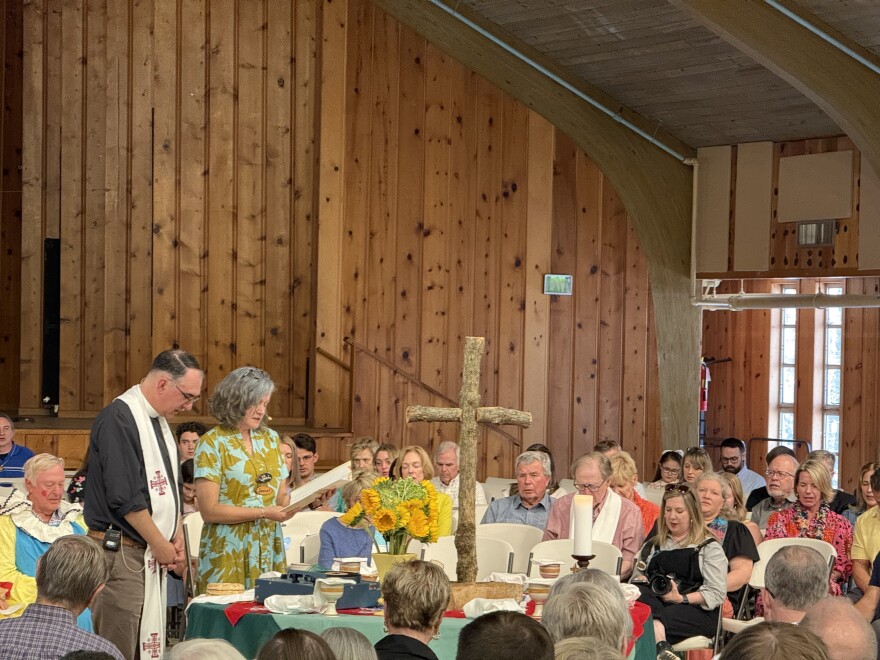 People surround an altar in Hutto Auditorium at Camp Sumatanga as they hosted a memorial  honoring Nina Reeves