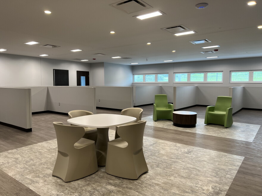 An open room with tables and chairs and windows along one wall. 