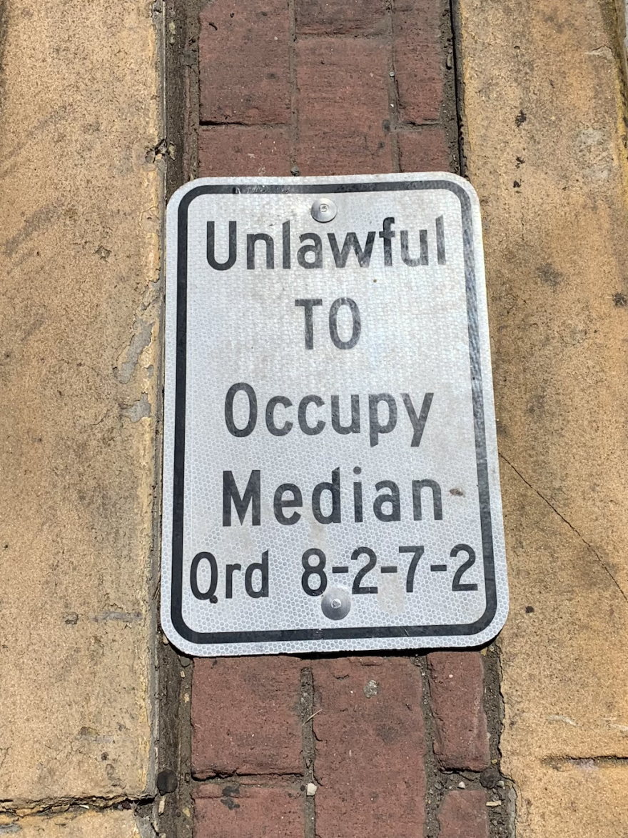 A sign bolted to a median that outlines the new ordinance being enforced