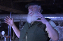 A man in a hat talking in a dark room.