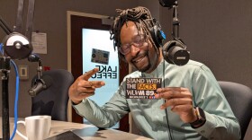 Antoine Carter poses in studio with a WUWM "stand with the facts" sticker