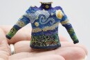 a tiny sweater knit with the pattern of the Van Gough painting Starry Night, sits in a persons hand.