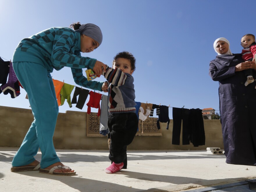 A Syrian refugee girl helps her brother walk as their mother watches at a mosque compound near Shebaa, Lebanon, on Oct. 28. The family suspects the boy has polio.