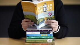 FILE - Amanda Darrow, director of youth, family and education programs at the Utah Pride Center, poses with books that have been the subject of complaints from parents on Dec. 16, 2021, in Salt Lake City.