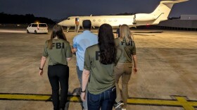 FBI officials escort Zobaidul Amin to a flight to Alaska to face federal charges related to child sexual eploitation.