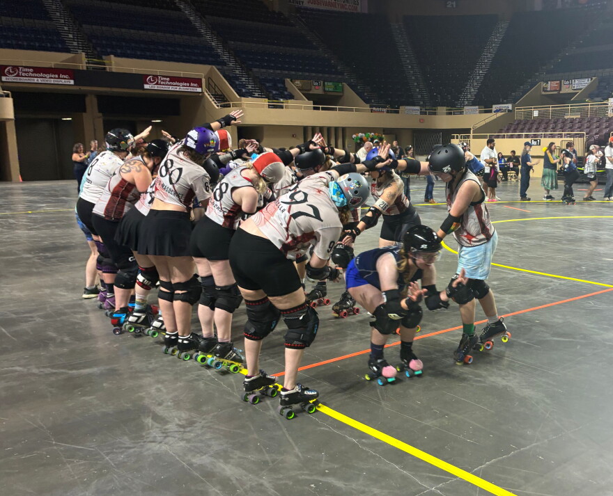 Twin Valleys Roller Derby skaters pass under a bridge made by the Carolina Bootleggers, a rival team.
