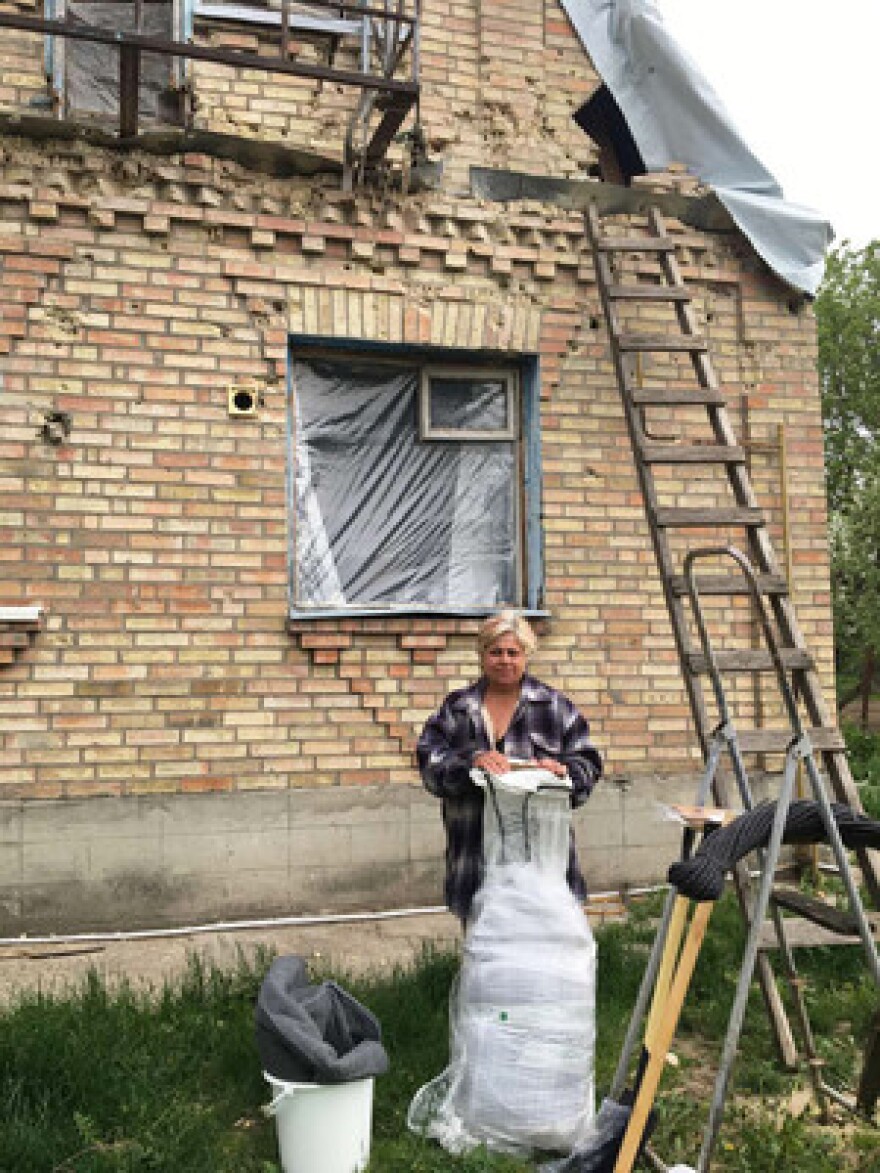 A Ukrainian woman named Olga stands outside her home in Ukraine. She recently collected shelter kits with tools and rope, high thermal blankets, hygiene kits including items like soap, washing powder and toothpaste, solar lights, buckets and water carriers.