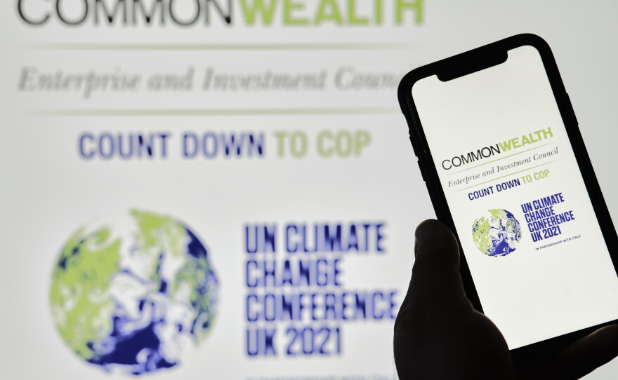 A hand holds a mobile phone with the COP26 logo on screen.