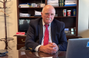 Stern man with mustache at desk