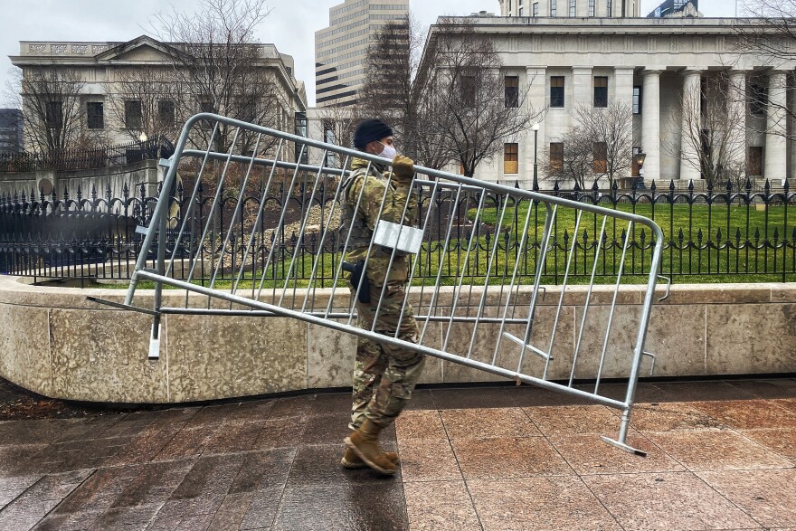 An Ohio National Guardsman moves barricades to assemble a gathering area for some of the television camera people who will be filming the protest. 