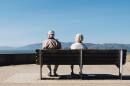 Man and woman sit on a bench facing the sea