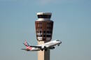 An airplane flies past the air traffic control tower 