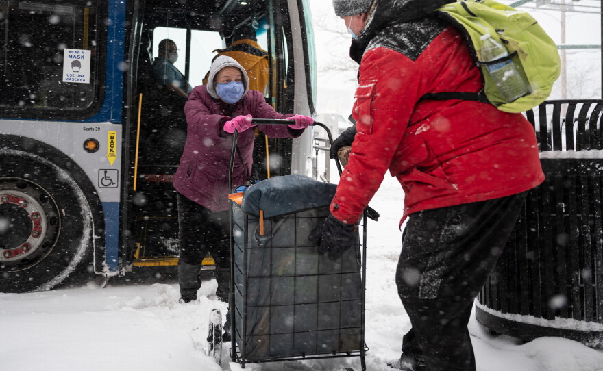 Alex Cambreren helps Antoinette Prece off the bus before boarding in the Fair Haven neighborhood of New Haven, Connecticut, as snow comes down during the state’s first major snowstorm of the year on Feb. 1, 2021.