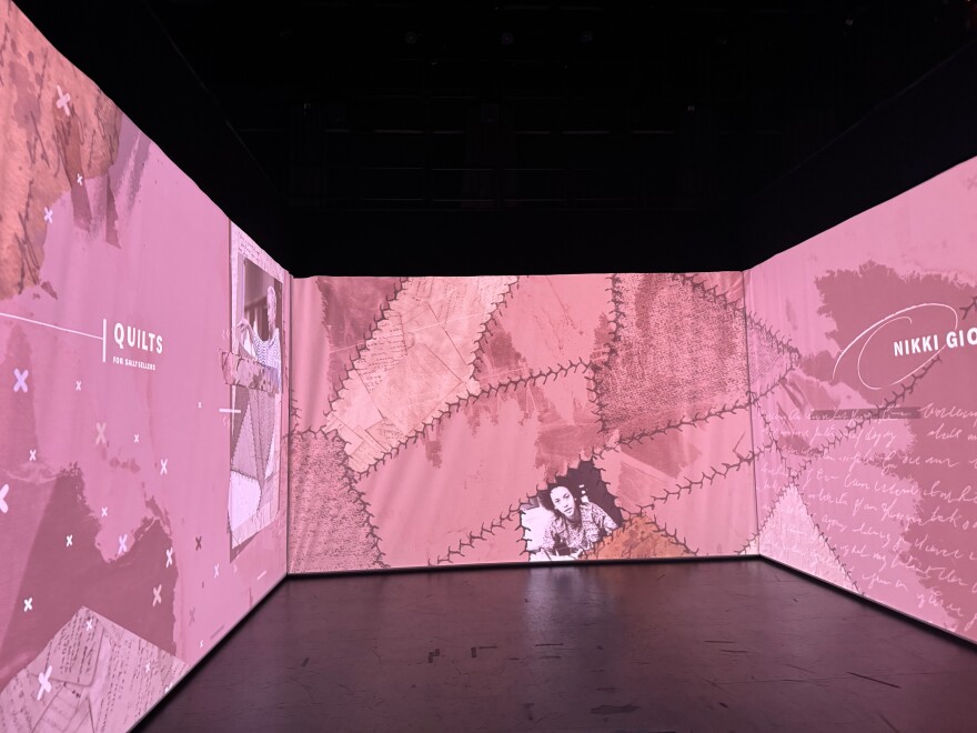 A pink graphic inside a three-paneled room, with Nikki Giovanni's face, with the word "quilts" on the left hand side. 