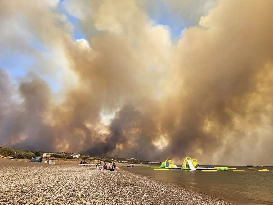 Clouds of smoke from a forest fire rise to the sky on the island of Rhodes, Greece, Saturday, July 22, 2023. A large blaze burning on the Greek island of Rhodes for the fifth day has forced authorities to order an evacuation of four locations, including two seaside resorts.