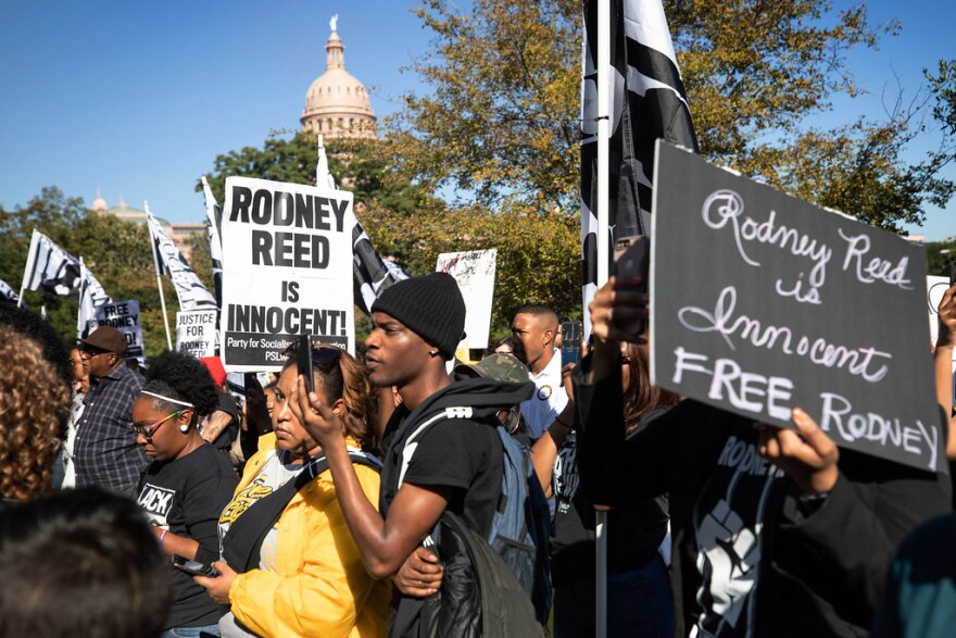 A group of demonstrators holding signs saying Rodney Reed is innocent with the Capitol dome in the background. 