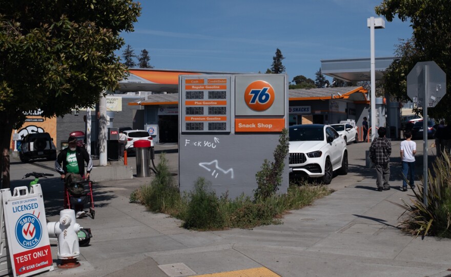 A 76 gas station in Oakland. The price displayed has been graffitied with an expletive, and an arrow that points to a $7 price for premium.