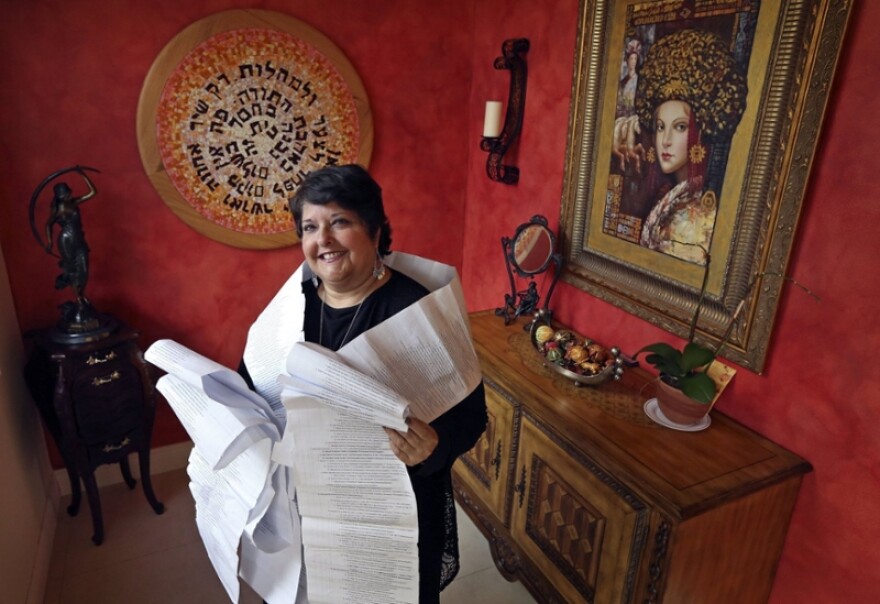 Genie Milgrom, pictured in 2013, stands in the entryway of her Miami home wrapped in a long family tree, filled with the names of 22 generations of grandmothers. Raised Catholic, Milgrom traced her family's hidden Jewish roots with the help of a trove of ancient family recipes written down by the women of her family over generations.