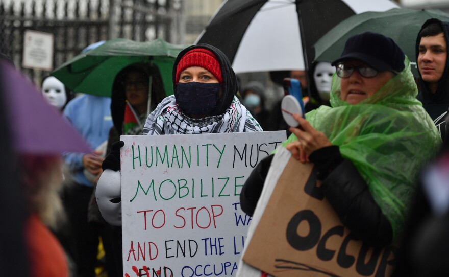 A protester marches with a sign asking to end Israel's occupation of Gaza.