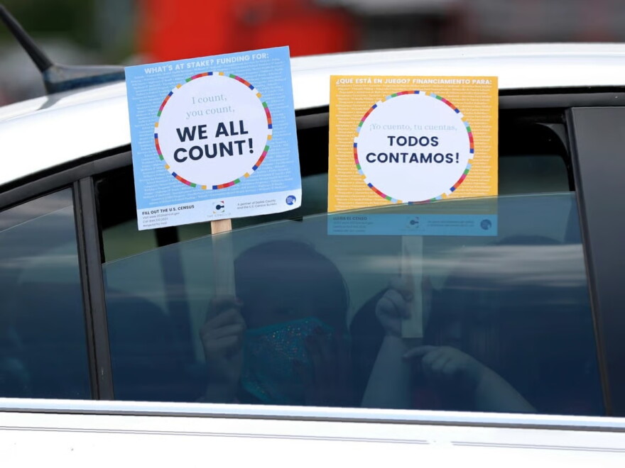 FILE: Two young children hold signs through the car window that make reference to the 2020 U.S. Census as they wait in the car with their family at an outreach event in Dallas, June 25, 2020.
