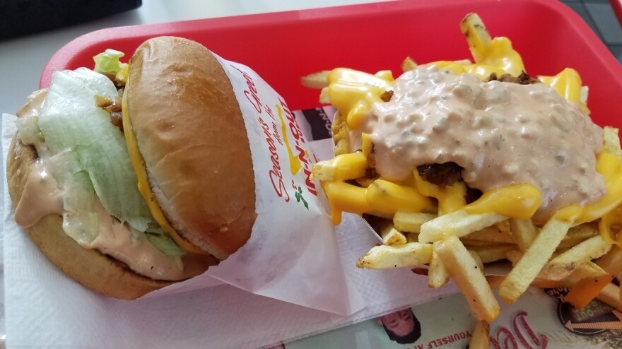 A sandwich and fries with sauce from In-N-Out sit in a red tray.