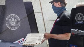 FILE - In this June 16, 2020, file photo, a voter casts their ballot at a polling station inside the Brooklyn Museum as early voting continues in the Brooklyn borough of New York. The civic ritual of casting a ballot has been disrupted by a global pandemic and dramatically animated by social unrest. And If the results of a frustrating, chaotic primary in Georgia are a measure, the notion of democracy itself will also be on the ballot in the November election. Congress is now considering sending $3.6 billion to states to help facilitate safe and fair elections as part of another round of relief funds to recover from the coronavirus pandemic. (AP Photo/John Minchillo, File)