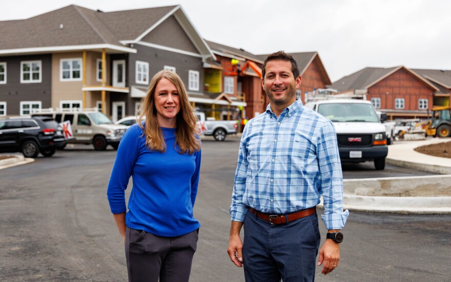 Two people pose for a photo at a residential construction site