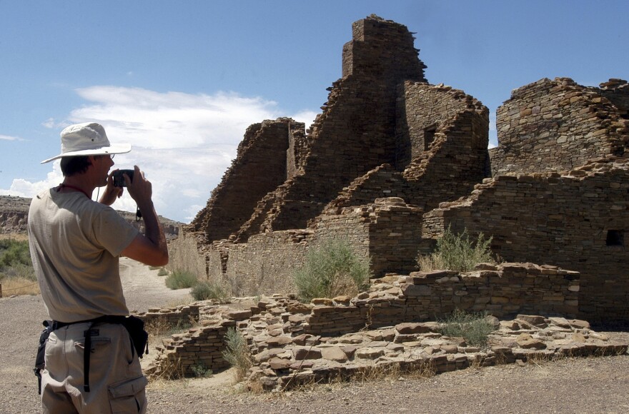 FILE - Tourist Chris Farthing, from Suffolks County, England, takes a picture of Anasazi ruins in Chaco Culture National Historical Park on Aug. 10, 2005, in New Mexico. Some Republican members of Congress voiced opposition Thursday, July 13, 2023, to the Biden administration’s recent move to withdraw hundreds of square miles of federal land in New Mexico from oil and gas development, including land around Chaco Culture National Historical Park, offering their support instead to legislation that would unravel the ban. (AP Photo/Jeff Geissler, File)