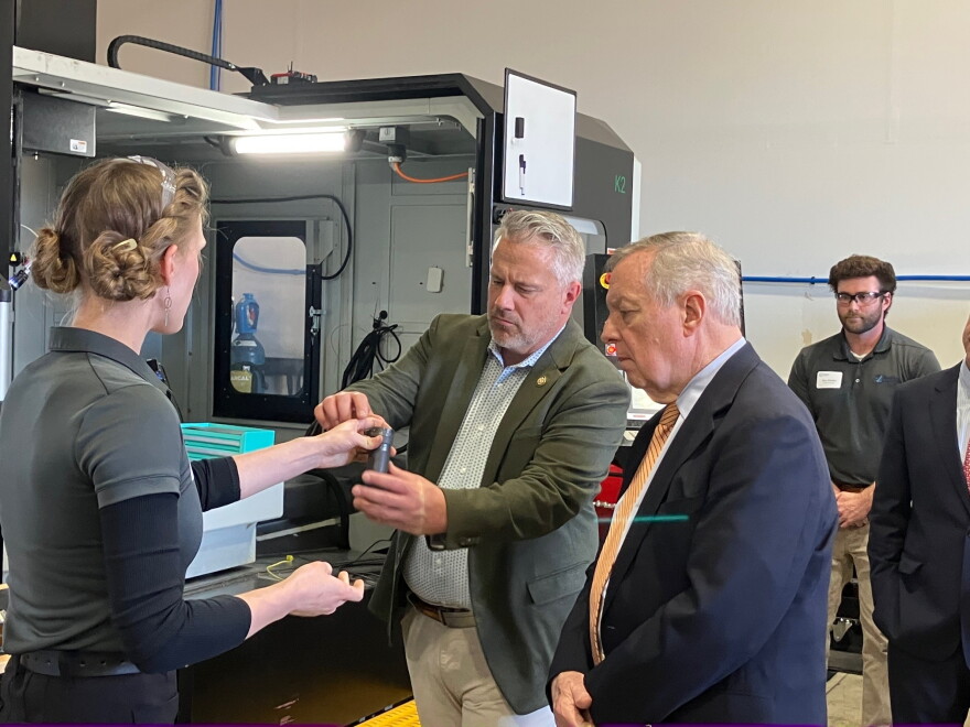 U.S. Rep. Eric Sorensen (D-Moline), center, and U.S. Sen. Dick Durbin (D-Illinois) look at a part produced by ASTRO America Midwest, during a plant open house at their Moline facility, Thursday, Oct. 29. 2026.