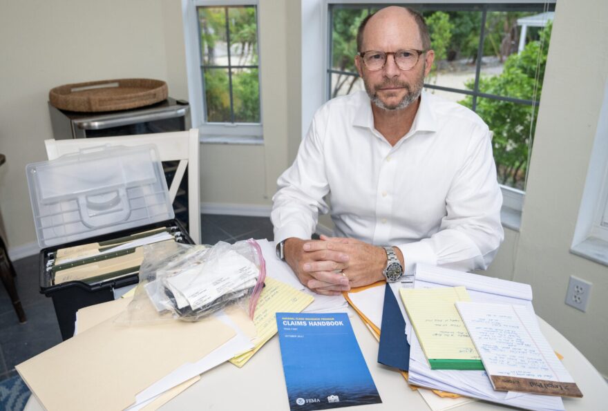 Chauncey Goss at his kitchen table with stacks of papers.