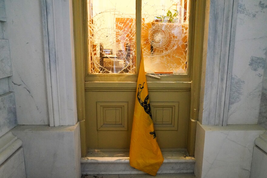 A flag hangs between broken windows outside the U.S. Capitol