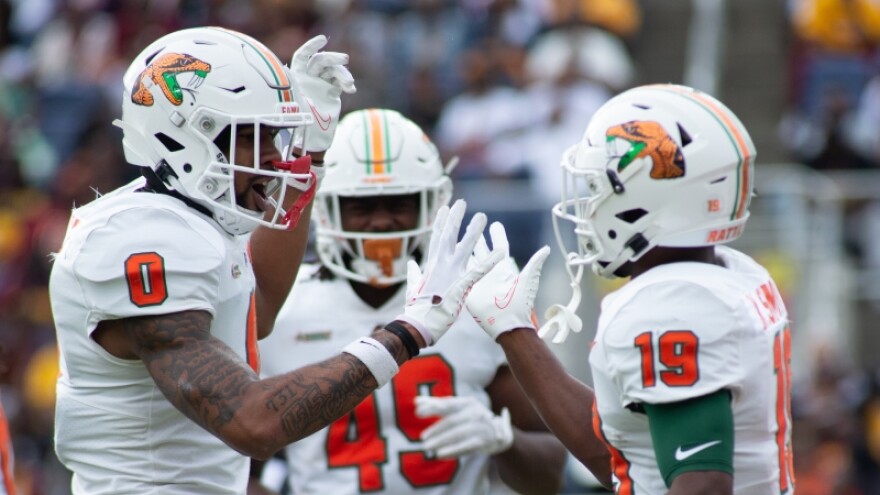 Football players in white jerseys high five each other