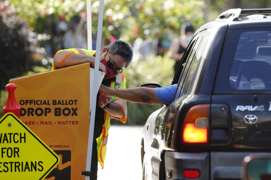 FILE - In this Nov. 3, 2020, file photo, an attendant helps a driver drop off a ballot on Election Day in Honolulu. The Hawaii Supreme Court dismissed an elections complaint challenging the entirety of the Nov. 3, general election in the islands, clearing the way for the results of the state's presidential vote to be certified. (AP Photo/Marco Garcia, File)