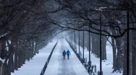 Two people walk along the National Mall as snow falls, Sunday, Jan. 25, 2026, in Washington.