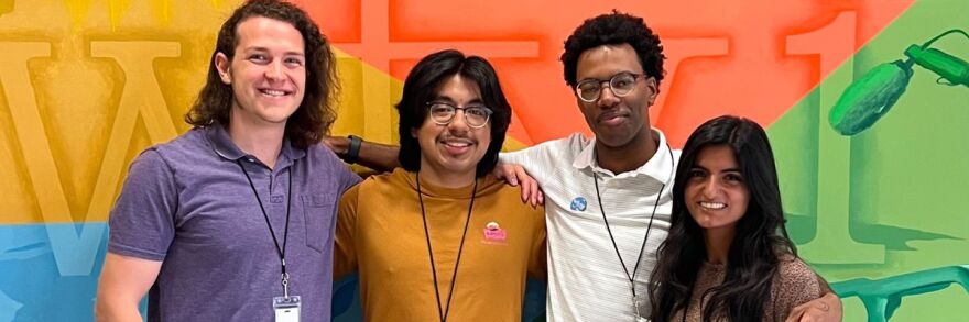 Interns posing in front of colorful WFYI lobby mural