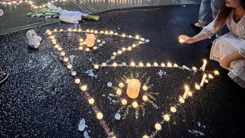 A candle arranged in the shape of the Nepali flag at a vigil for Rasuwa flood victims outside an Albany temple. 