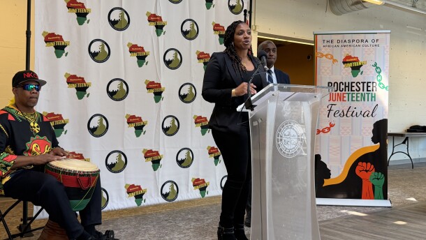 Nikia Washington, coordinator of the Rochester Juneteenth Festival, delivers closing remarks during a ceremony announcing this year's event. Behind her to the right is Simeon Banister, president and CEO of the Rochester Area Community Foundation and leader of The Greater Rochester Martin Luther King Jr. Commission, and drummer Shenuti Nehast Kawaida.