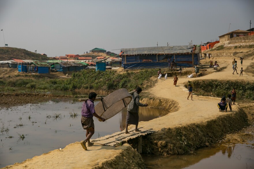 Men carry a cement ring that will serve as part of a holding tank for a toilet being built in the Kutupalong camp. Many of the current toilets are just open pits that could leak sewage in the coming rainy season.