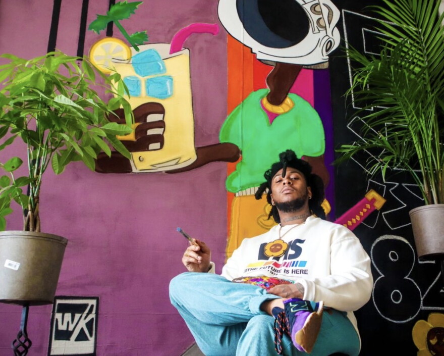 Black man sitting in front of artwork