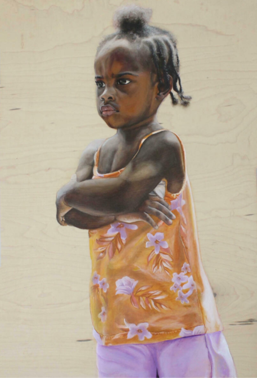 A little girl stands with her crossed, a slight pout on her face.