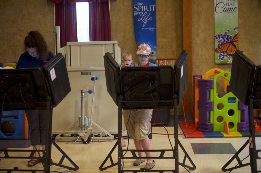Elisabeth Ford (center), 33, holds her son, Harrison, 8 months, while casting her vote at the Trucksville United Methodist Church polling station during the 2018 Pennsylvania Primary Election in Trucksville.