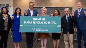 TGH CEO John Couris, USF President Rhea Law, and Dean of the USF College of Nursing Usha Menon holding a banner thanking Tampa General Hospital for the donation.