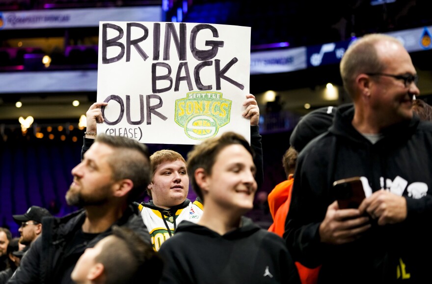 A fan holds a sign that reads Bring Back our Sonics at an NBA game