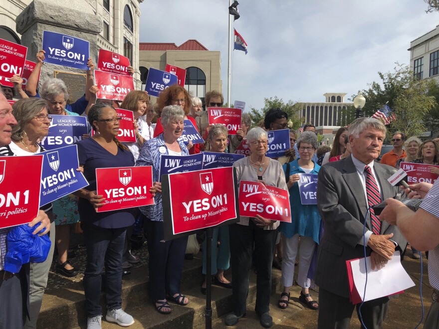 Supporters of Missouri's redistricting ballot measure hold signs behind former state Sen. Bob Johnson during a news conference in Jefferson City, Mo., in August.