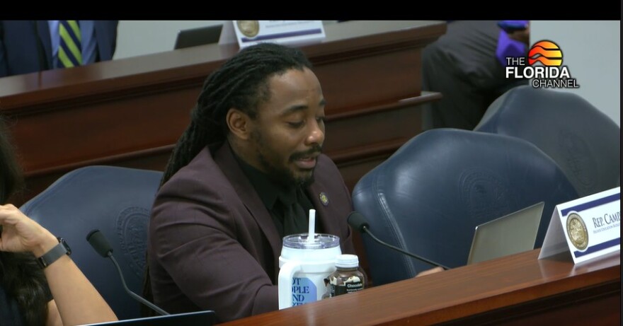 A man with braids pulled back speaks at a mic in a House subcommittee meeting
