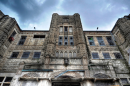 The front of the Missouri State Penitentiary building towers as dark, shadowy clouds loom above.