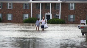 A couple wades through floodwaters in Paducah, Ky., Tuesday, July 7, 2015. Heavy rain in part of western Kentucky has led to multiple water rescues.