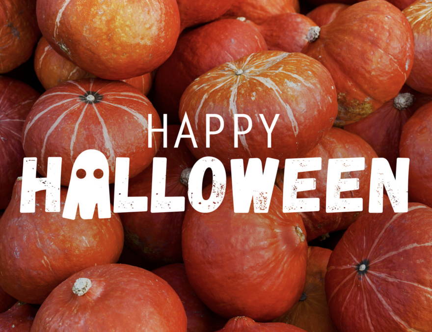 A collection of bright orange and red pumpkins fills the background behind large white text reading “Happy Halloween,” with a small ghost incorporated into the lettering.