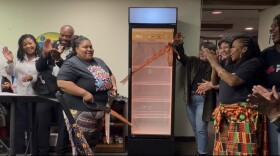 Melody McCurtis (center), Deputy Director of Metcalfe Park Community Bridges, cut the ribbon on a new community powered fridge at the organization's headquarters.
